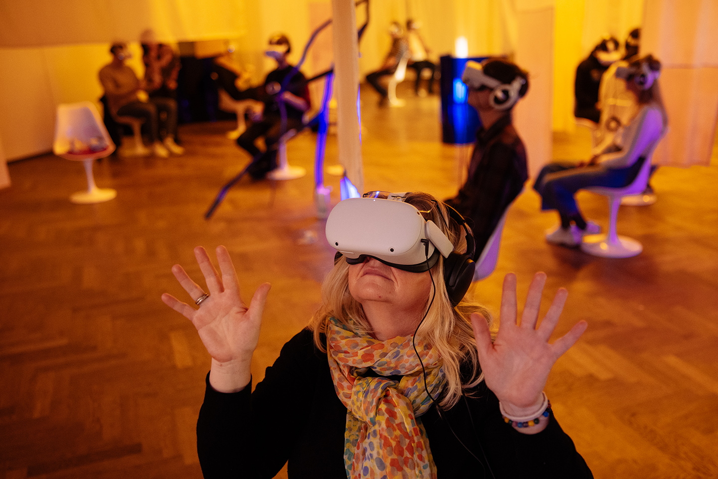 Jeden svet VR 2023 Žena sedí a na očích má brýle pro sledování projektu ve virtuální realitě.
