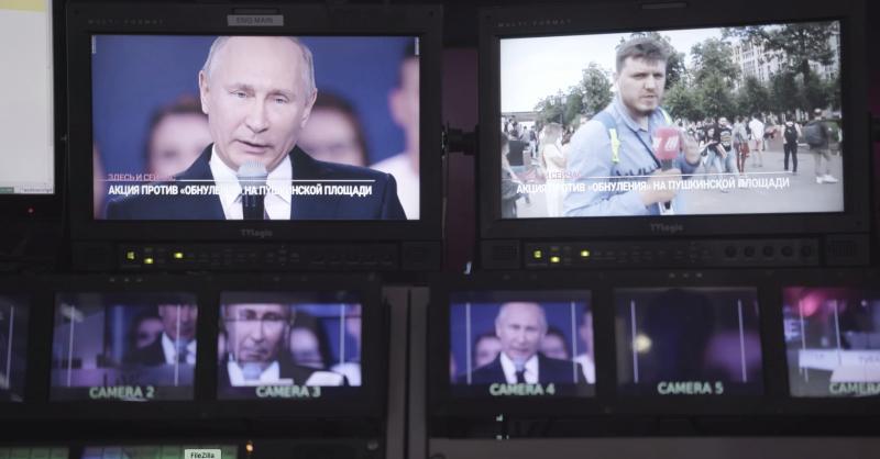 Monitory televizního studia. Na jednom z nich mluví do mikrofonu ruský prezident a na druhém je zachycený TV reportér a protestní akce.