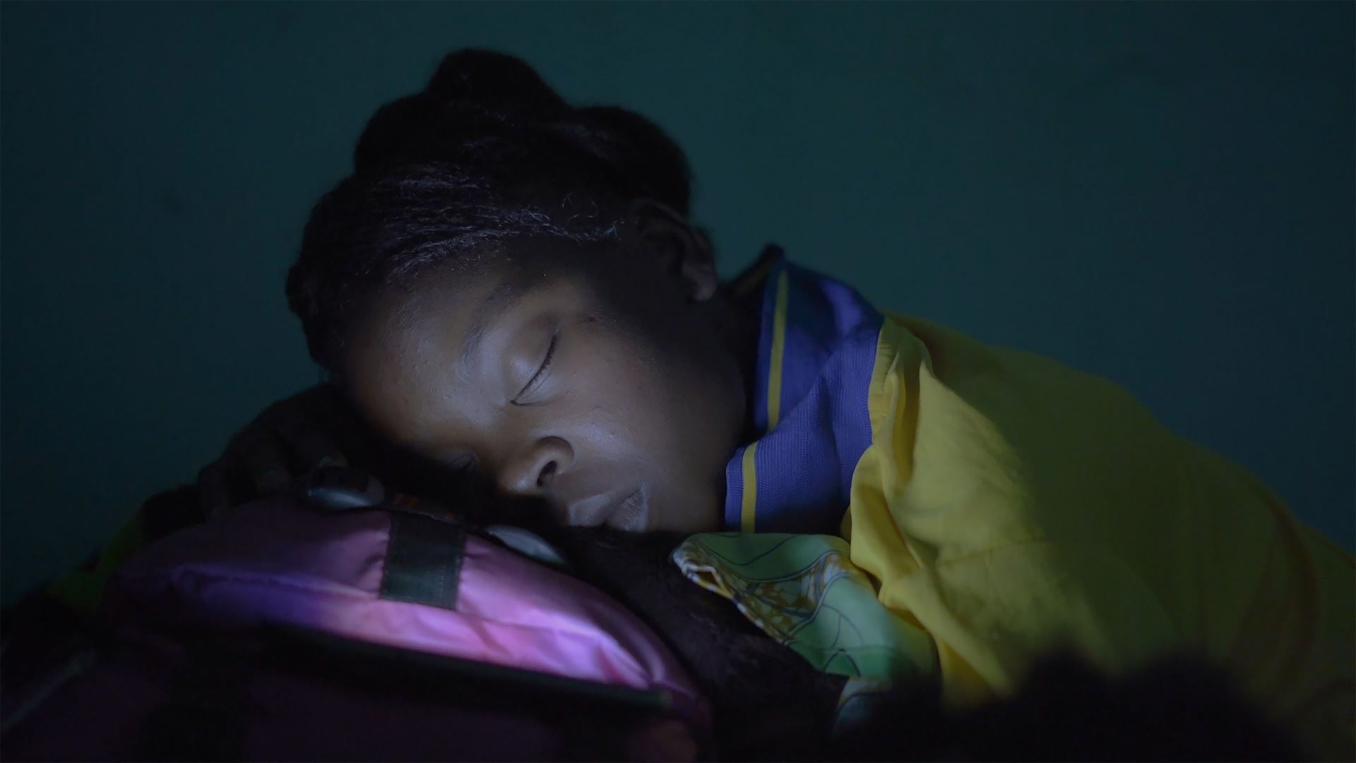 Mladá žena tmavé pleti z Burkiny Faso spí na své cestovní tašce.