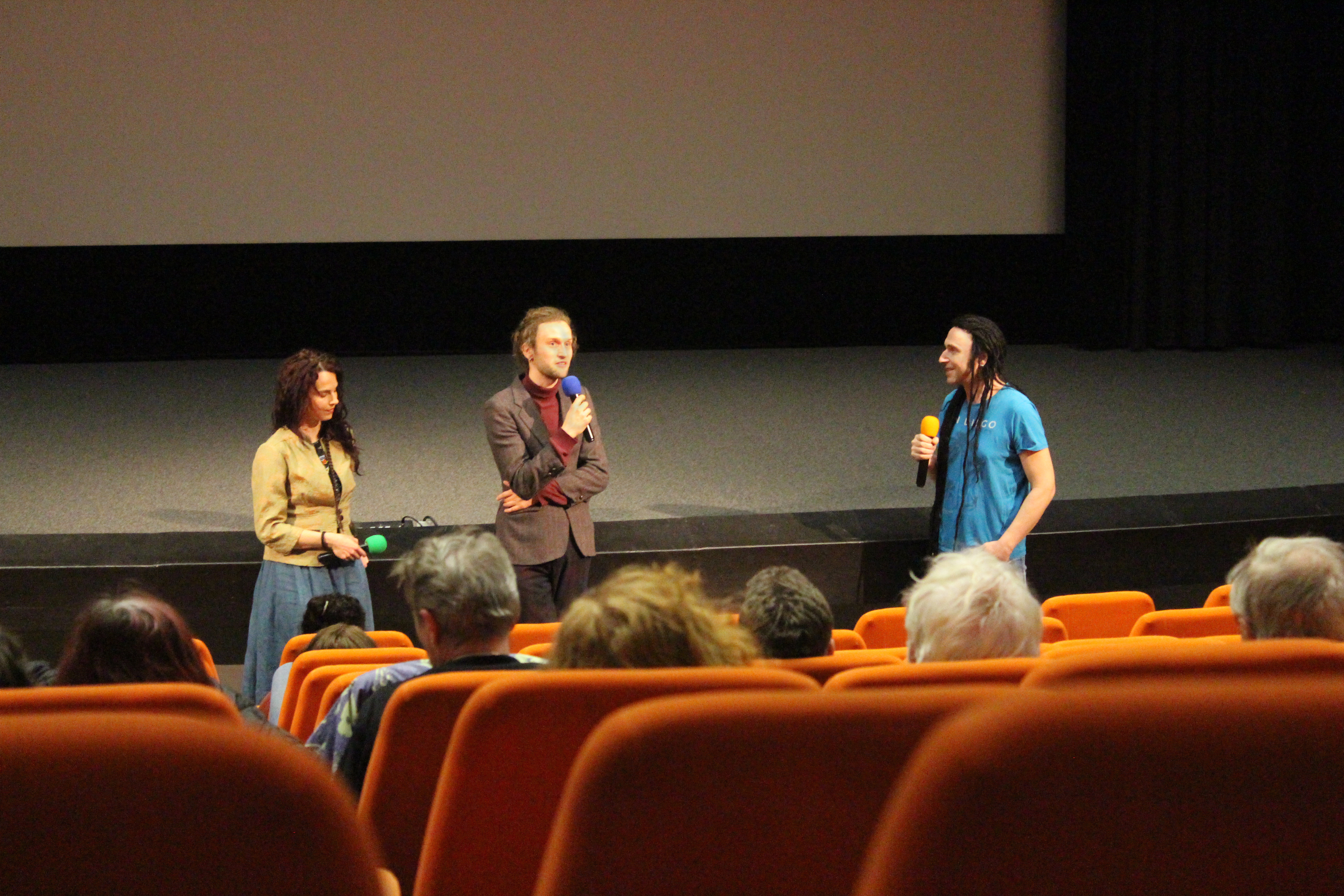 Tři debatující stojí před publikem