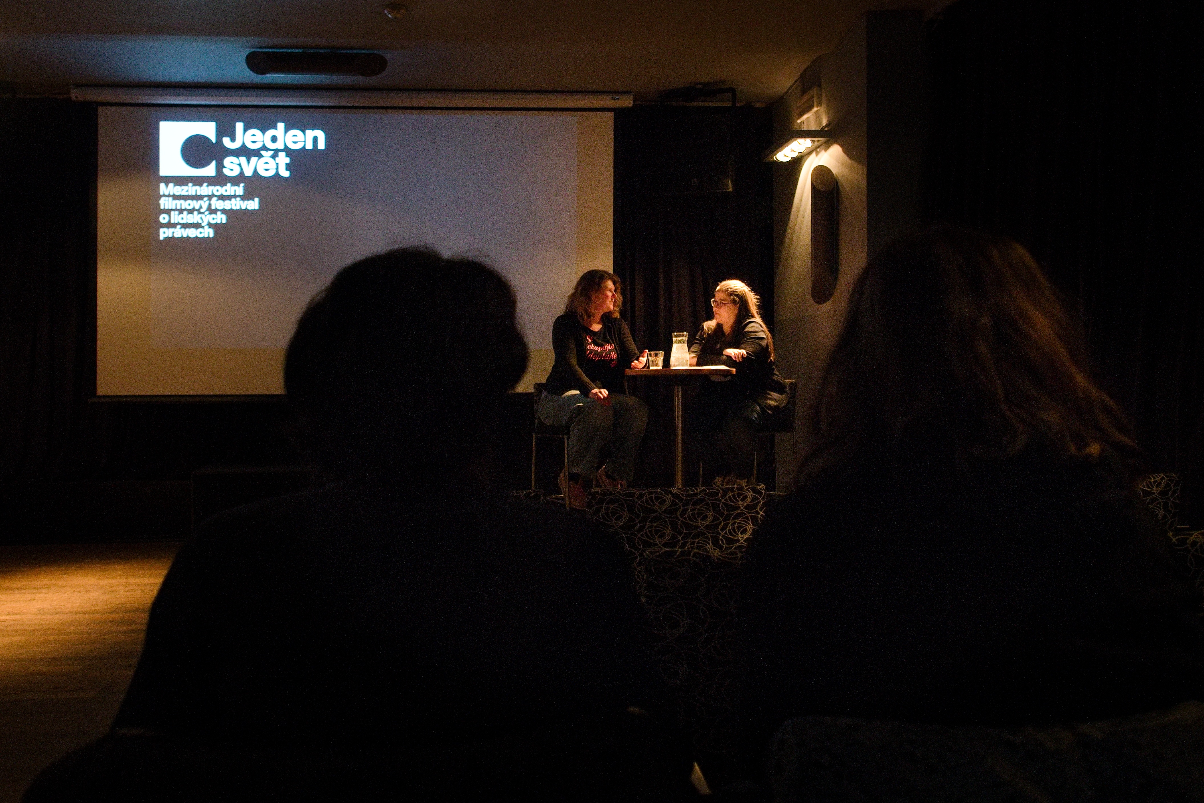 Jeden svět: filmy a debaty o lidských právech na konci března v Opavě Promítací sál. U plátna sedí a debatují dvě ženy.