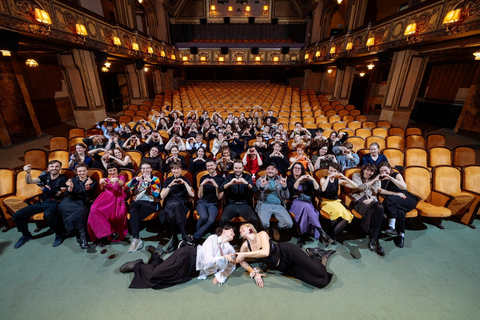 V sále Lucerna sedí v hledišti celý festivalový tým a každý ukazuje rukama srdíčko.