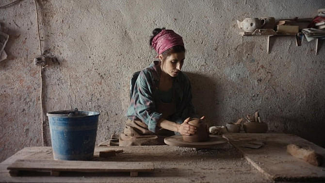 Rodičovská trápení mají mnoho podob Žena sedí v dílně u hrnčířského kruhu a rukama tvaruje keramickou nádobu z hlíny; na stole vedle ní stojí modrý kbelík a kolem jsou rozložené hrnčířské nástroje.