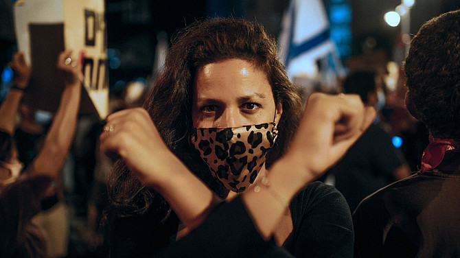 Budějovice v epicentru lidských práv: Jeden svět přiváží Šimona Pánka i filmové hrdinky Žena s rouškou s leopardím vzorem stojí v davu lidí na protestu a zvedá ruce.