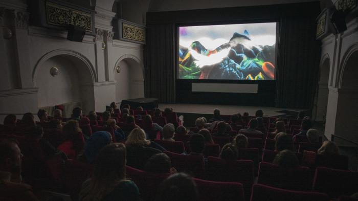 Najděte si svůj film Diváci v potemněném kinosále sledují film na plátně.