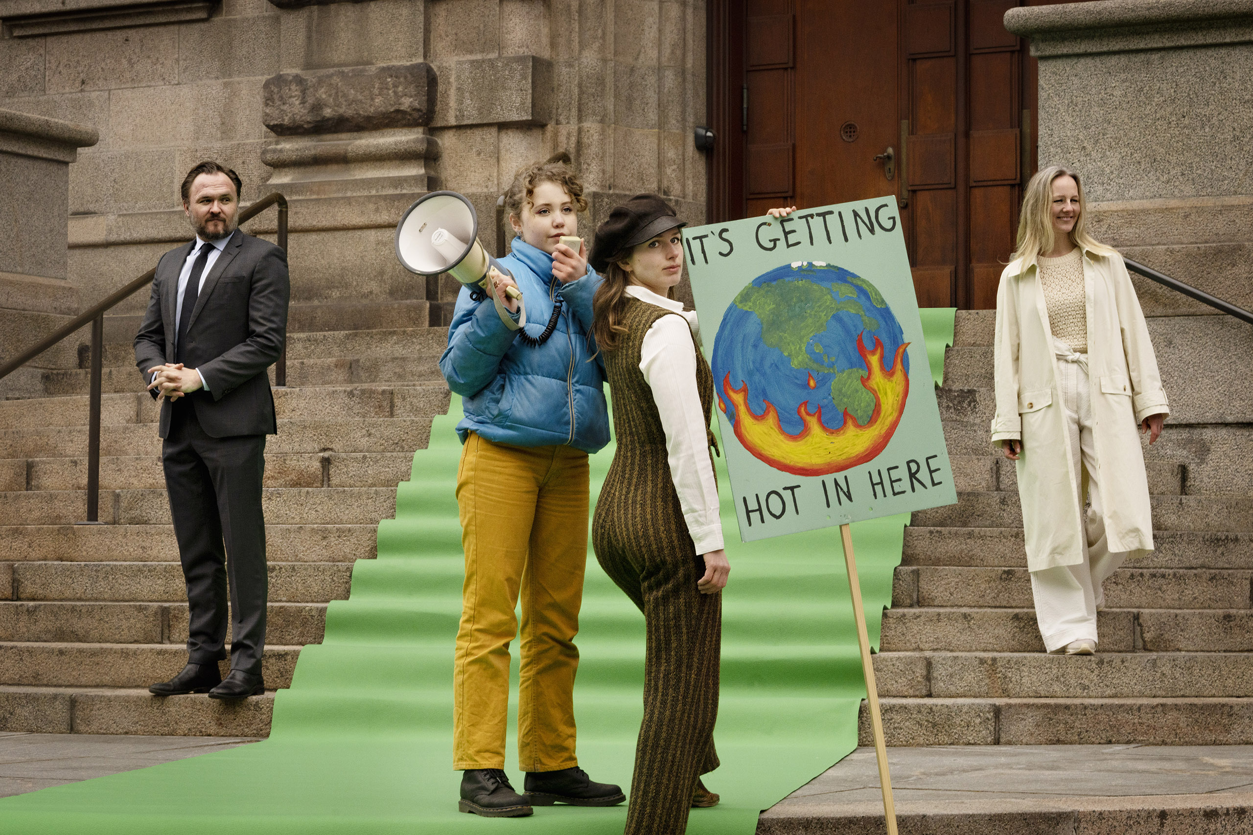 Na fotce jsou mladí lidé, kteří protestují s bannery proti klimatické krizi. Na banneru je namalovaná Země a nápis – už to trochu přihořívá.